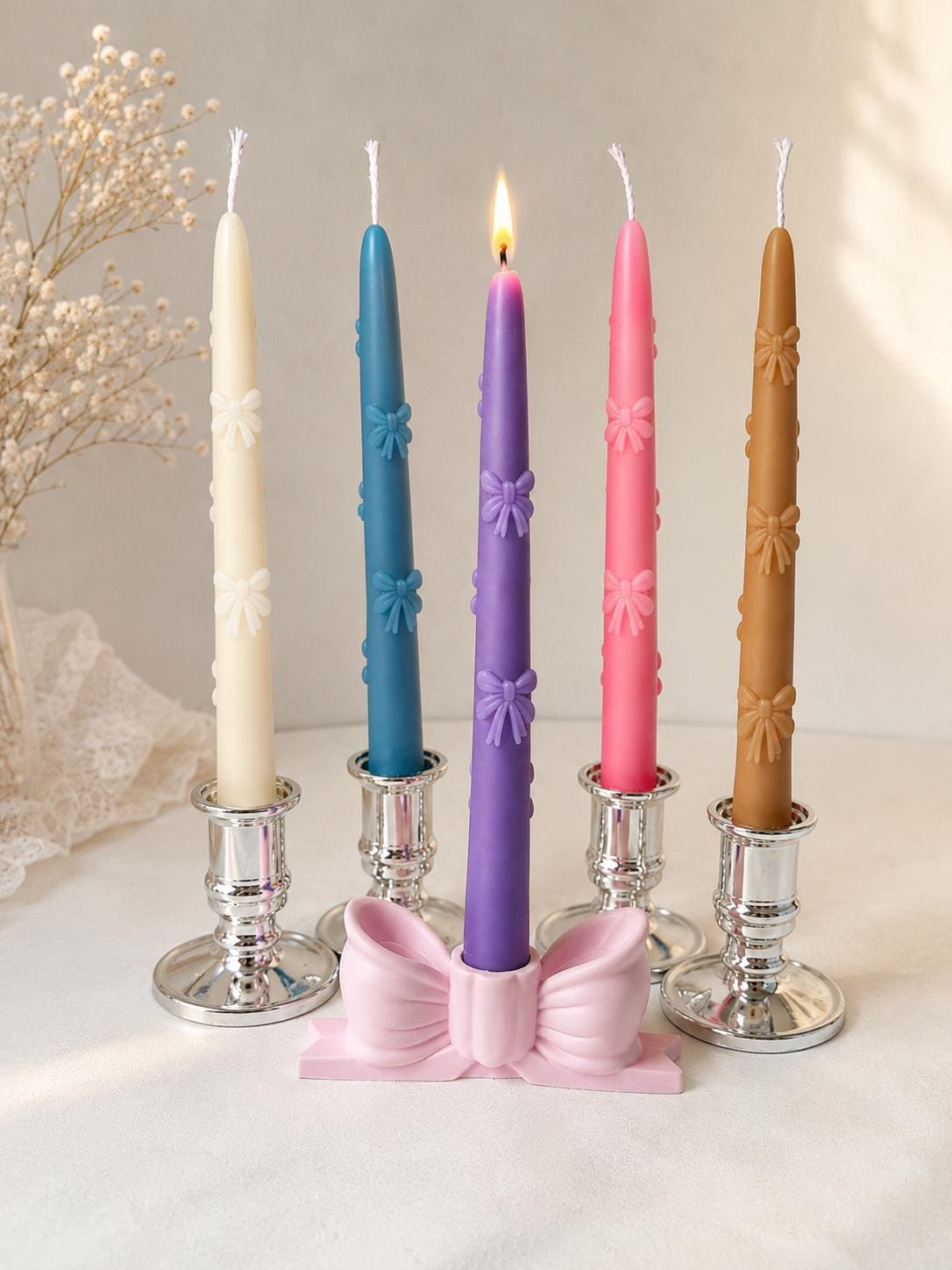 Colorful handmade floral taper candles displayed in elegant silver candlestick holders