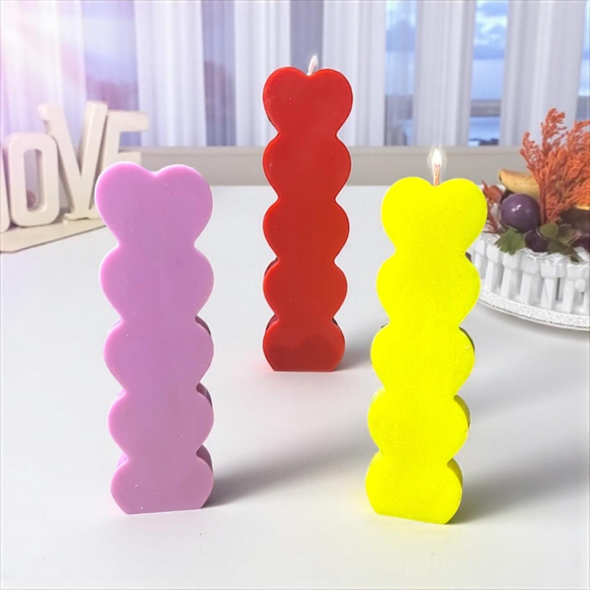 Colorful handmade bubble pillar candles in pink, red, and yellow displayed as modern home décor