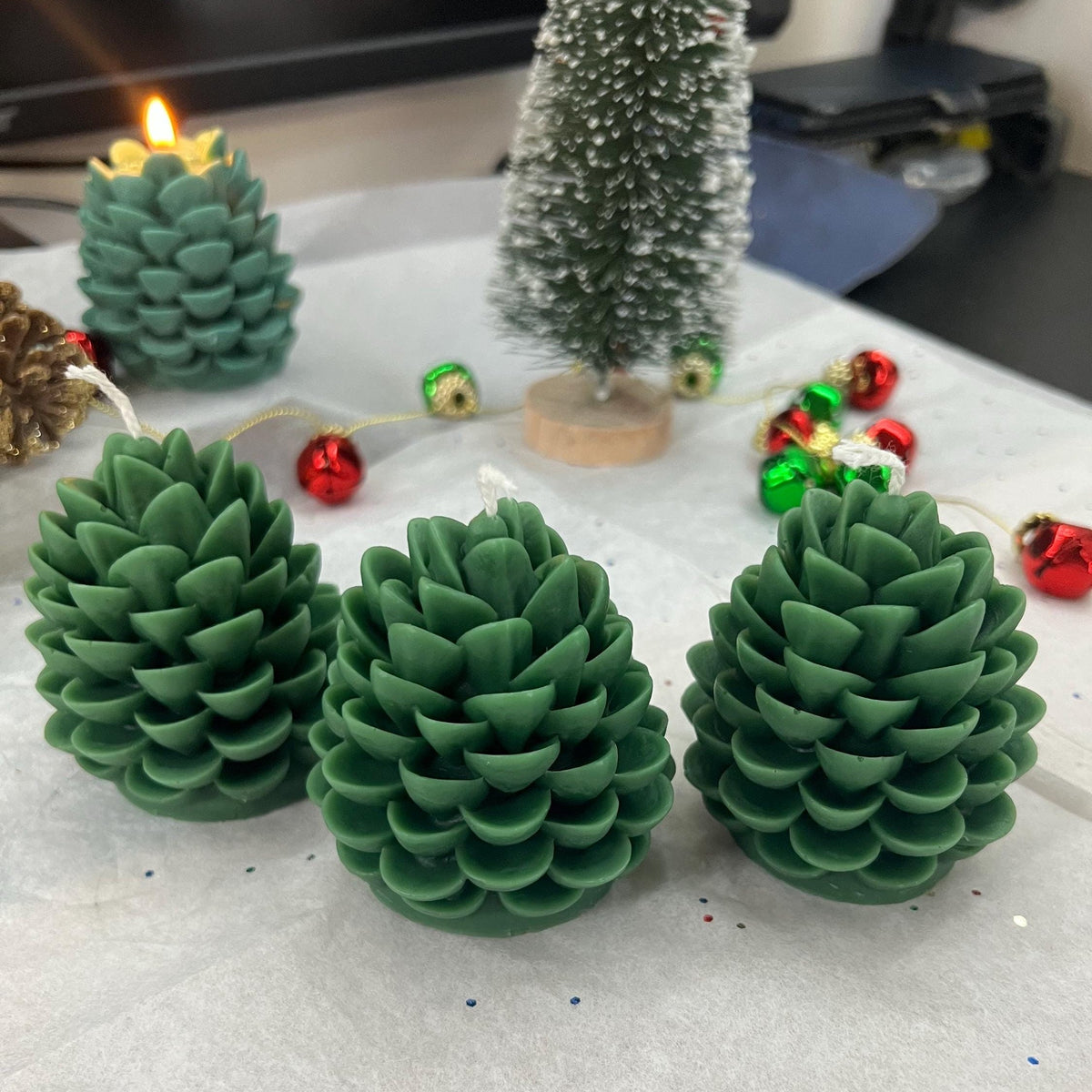 Handmade pine cone candles in forest green displayed as festive Christmas home décor