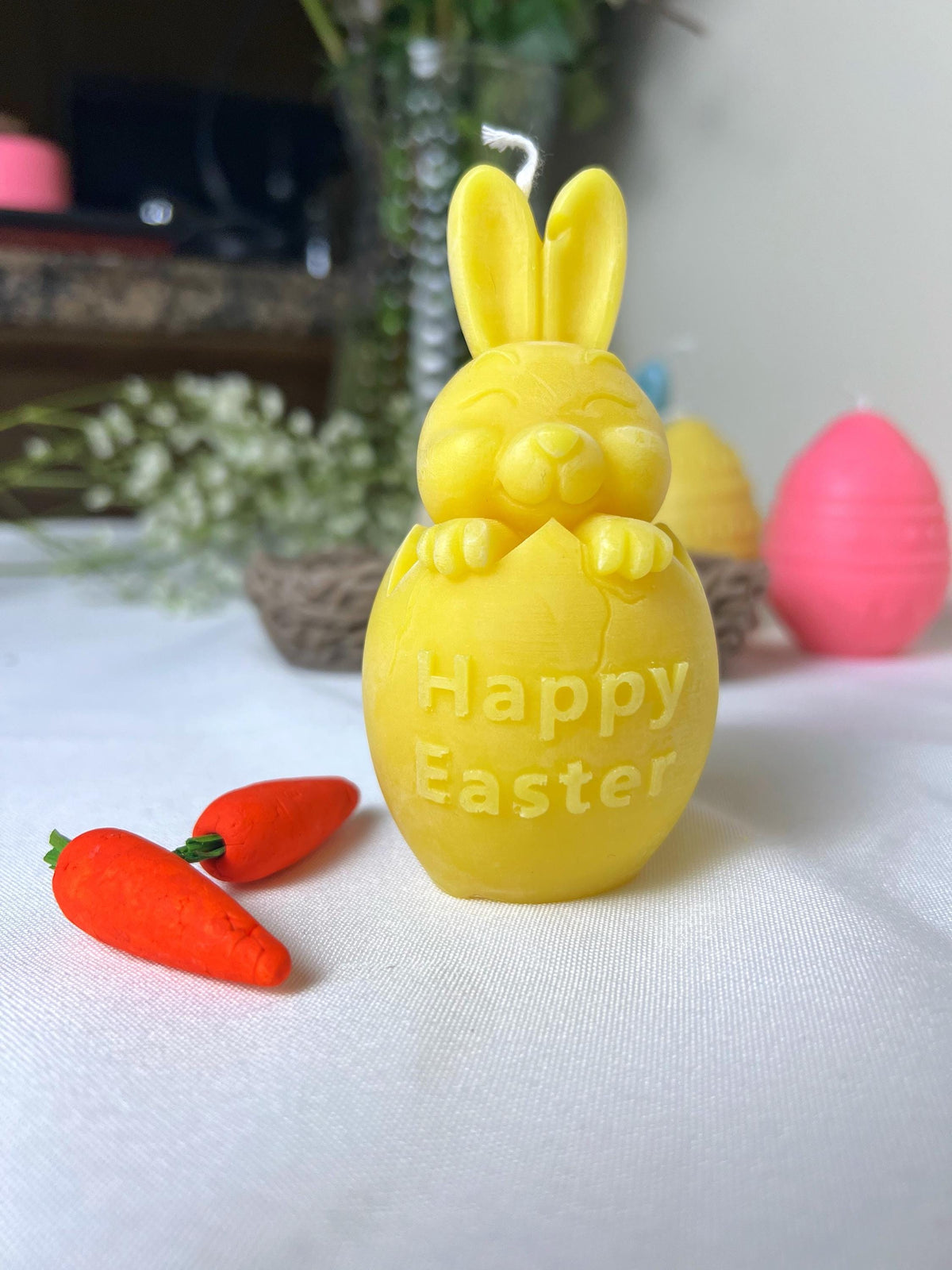 Yellow Happy Easter bunny candle with carrot details on a white background