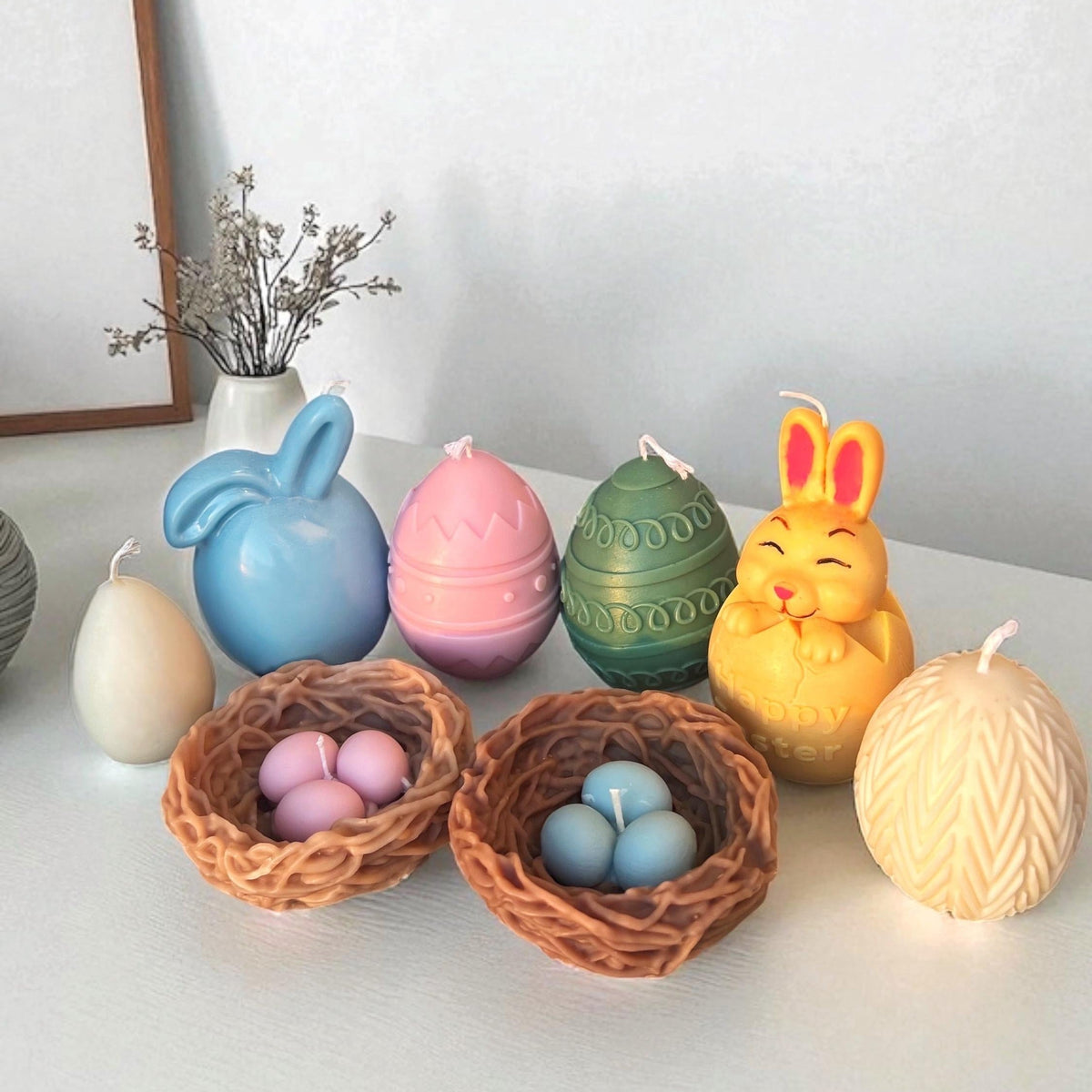 Handmade Easter candle collection featuring bunny, decorative eggs, woven bird nests with egg candles, and textured egg-shaped candles in soft pastel colors.