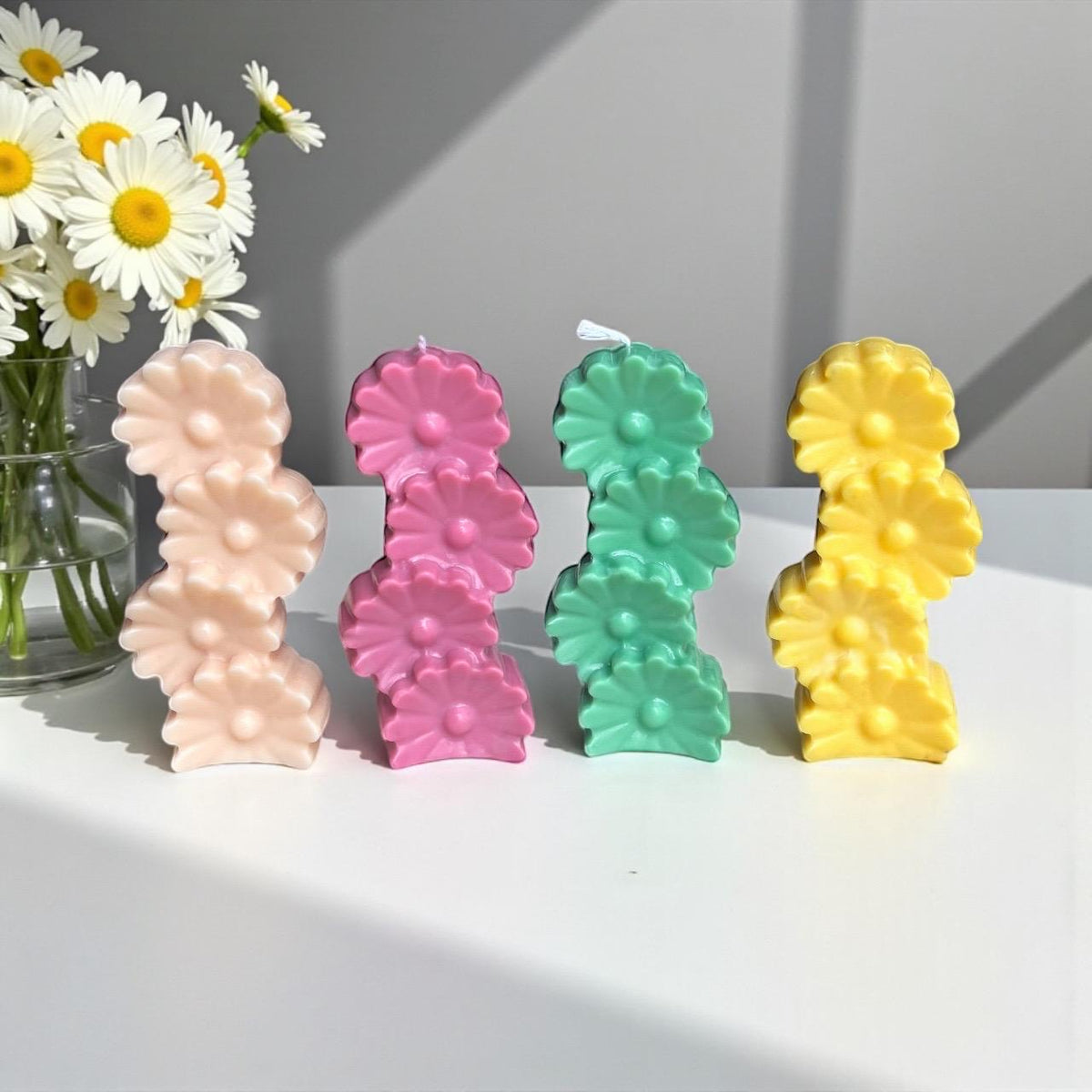 Handmade daisy pillar candles in pastel colors displayed as cheerful spring home décor